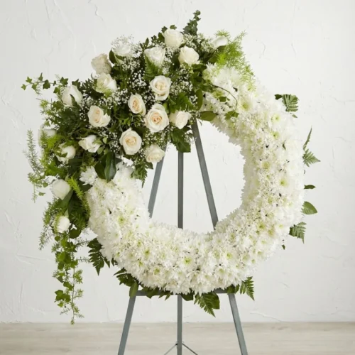 Corona de flores blancas en pedestal para velorio o entierro.