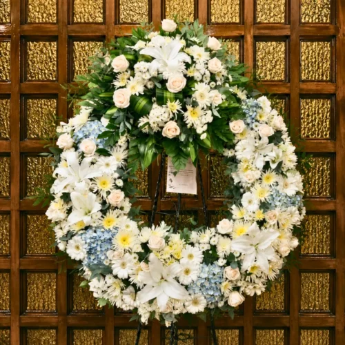 Corona fúnebre blanca con lirios, rosas y hortensias celestes en Guatemala